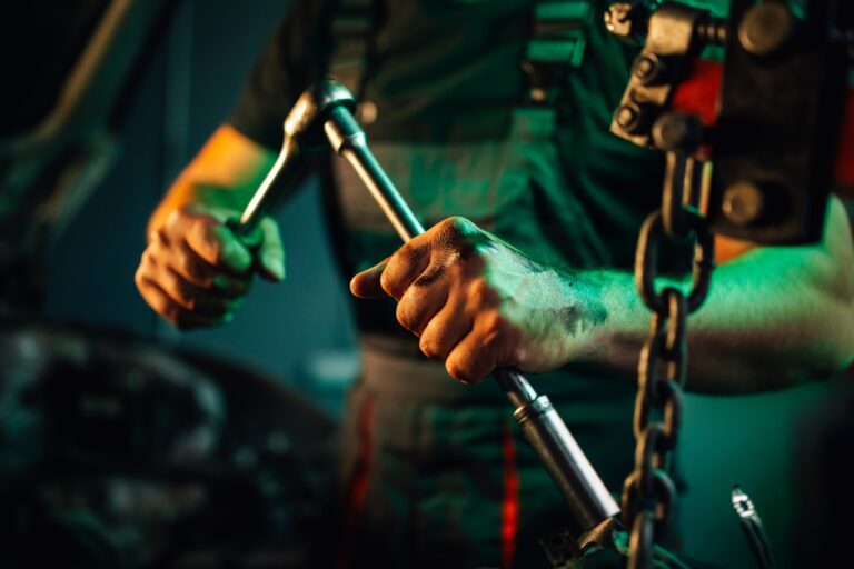 Mechanic tightening a bolt on an engine part with a ratchet wrench.