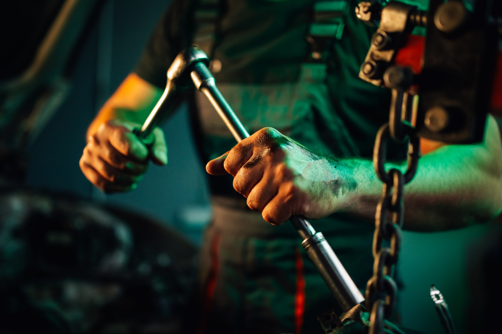 Mechanic tightening a bolt on an engine part with a ratchet wrench.